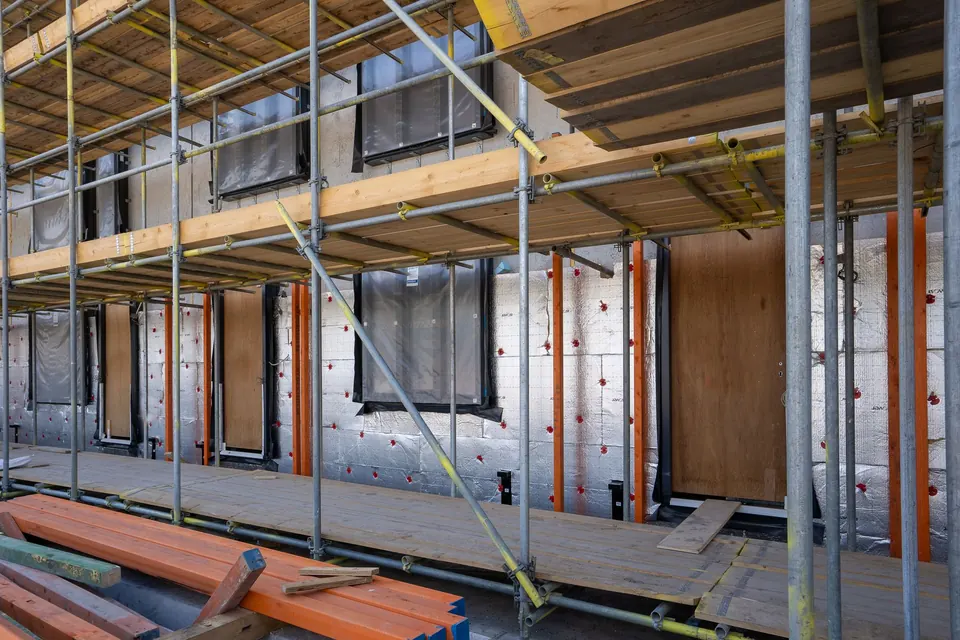 Gerüst vor einer Gebäudefassade mit angebrachten Dämmplatten im Rohbau
