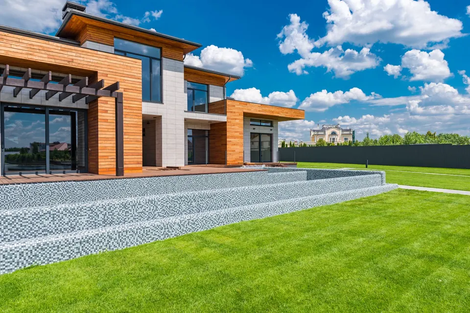 Modernes Wohnhaus mit Holzfassade und großen Fenstern an einer grünen Rasenfläche