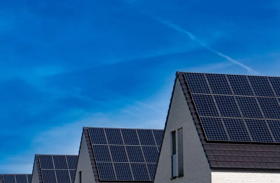 Reihenhäuser mit Satteldächern und Solarmodulen vor tiefblauem Himmel